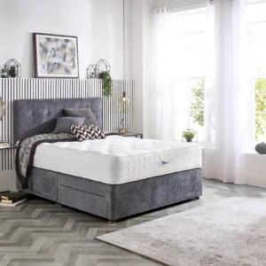 A detailed product image showing the internal layers of the Natural Luxury 1400 Deluxe mattress, including the pocket springs, foam, and natural fillings. The image also displays the full mattress on a divan base in a bedroom setting, highlighting its elegant finish and a tag with "10" indicating a 10-year warranty.