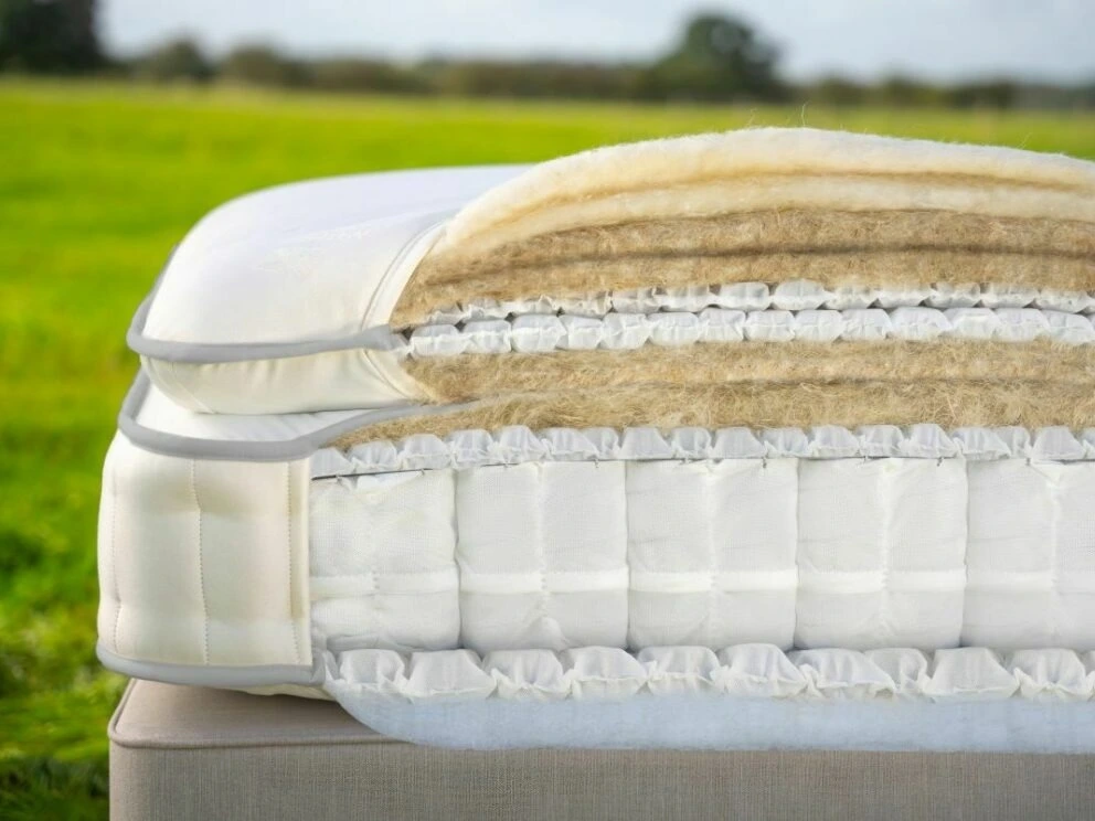 A screenshot of the Harrison Spinks Asscher Pillowtop 11,000 mattress product page. The images show a full mattress on a pink divan base, a close-up of the mattress's quilting, and a list of key features including 11,000 springs and natural fillings.