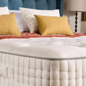 A screenshot of the Harrison Spinks Emerald 16,500 mattress product page. The images show a full mattress on a blue divan base, a close-up of the mattress's quilting, and a list of key features including 16,500 springs and natural fillings.