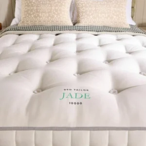 A screenshot of the Harrison Spinks Jade 10,000 mattress product page. The images show a full mattress on a green divan base, a close-up of the mattress's quilting, and a list of key features including 10,000 springs and natural fillings.