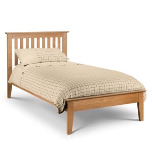 A full shot of the Salerno Shaker Bed, showing its two-tone finish with an ivory lacquer frame and solid white oak cappings on the headboard and footboard. The bed is styled with white bedding in a bedroom with a dark blue feature wall.