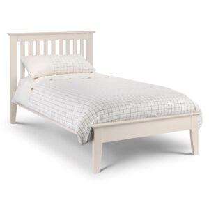 A full shot of the Salerno Shaker Bed, showing its two-tone finish with an ivory lacquer frame and solid white oak cappings on the headboard and footboard. The bed is styled with white bedding in a bedroom with a dark blue feature wall.