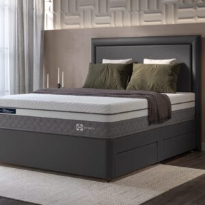 A full shot of the Venus 1500 Hybrid Mattress, shown on a dark grey divan base with storage drawers and a matching upholstered headboard, set in a contemporary bedroom. The mattress features a white top panel and a distinctive grey quilted side panel.