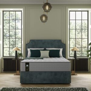 A full shot of the Venus 1500 Hybrid Mattress, shown on a dark grey divan base with storage drawers and a matching upholstered headboard, set in a contemporary bedroom. The mattress features a white top panel and a distinctive grey quilted side panel.