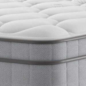 A luxurious shot of the Edison Luxury Plush Mattress, placed on a classic divan base with a curved upholstered headboard, featuring a large "NBF Awards - Bed Product of the Year" winner badge prominently displayed over the bed. The mattress has a deep quilted white top.