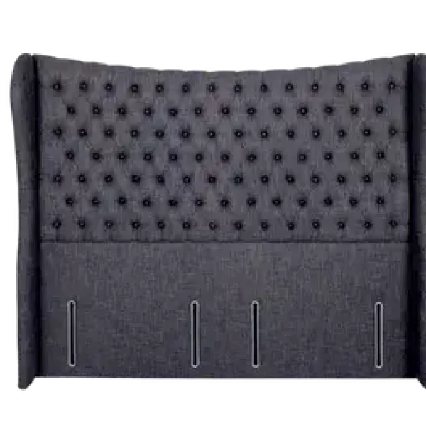 A sumptuous, extra-wide headboard with a deeply-buttoned centre panel and piped 'P' shaped wings, shown in a dark grey upholstered fabric. The headboard is shown against a plain grey background.