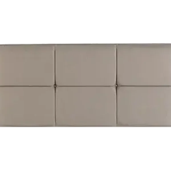 A modern, rectangular headboard in a light, neutral-colored upholstered fabric. The headboard has a hand-piped border and cushioned panels and is shown against a plain grey background.