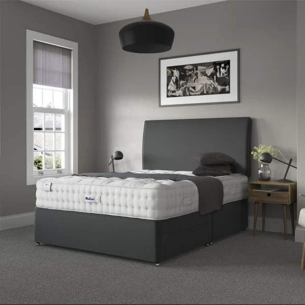 A detailed product image showing the internal layers of the Luxury Wool 2150 mattress, including the pocket springs and wool layers. The image also displays the full mattress on a divan base in a bedroom setting, highlighting its hand-tufted finish and a tag with "10" indicating a 10-year warranty.
