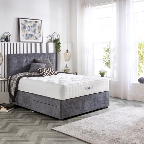 A detailed product image showing the internal layers of the Natural Luxury 1400 Deluxe mattress, including the pocket springs, foam, and natural fillings. The image also displays the full mattress on a divan base in a bedroom setting, highlighting its elegant finish and a tag with "10" indicating a 10-year warranty.