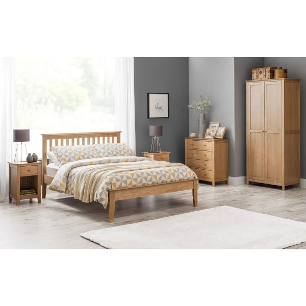 A full shot of the Salerno Shaker Bed, showing its two-tone finish with an ivory lacquer frame and solid white oak cappings on the headboard and footboard. The bed is styled with white bedding in a bedroom with a dark blue feature wall.