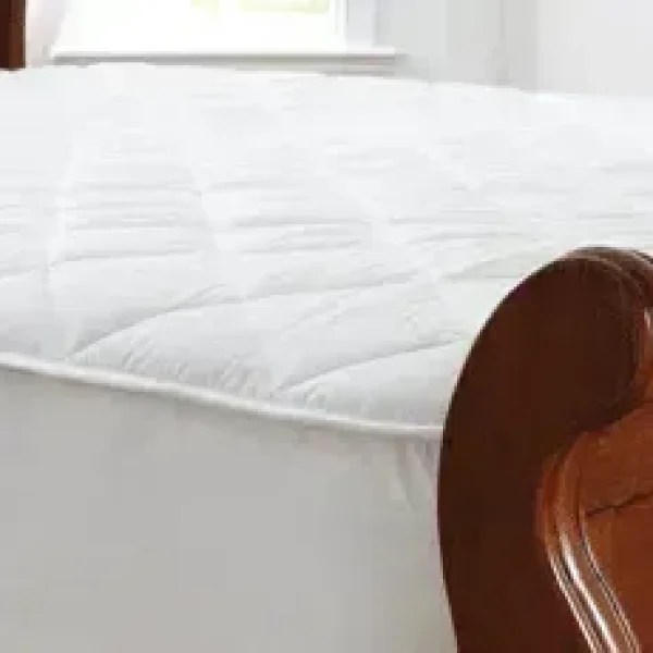 A close-up image of a white, quilted wool mattress protector on a bed. The image highlights the texture and quality of the fabric.