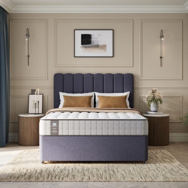 A full shot of the Chapman Extra Firm Mattress, shown on a matching divan base with a contemporary upholstered headboard. The mattress has a premium quilted white and grey top with the Sealy branding visible on the side panel.